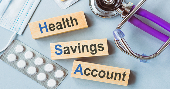 stethoscope, face mask, pills, blocks spelling out health savings account