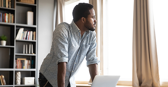 Man at his laptop looking out the window