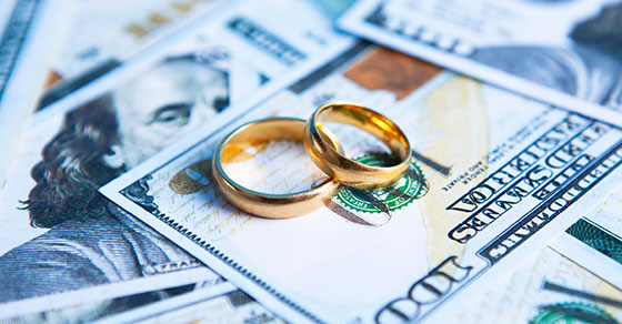 Wedding rings laying on $100 bills
